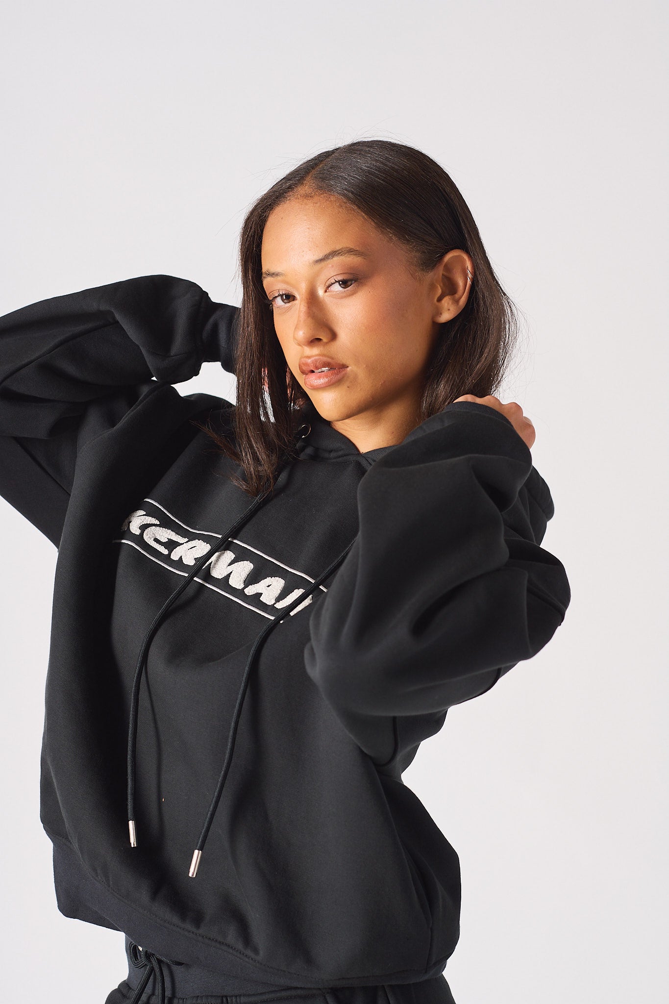 Close up of model holding drawstrings on womens black oversized hoodie