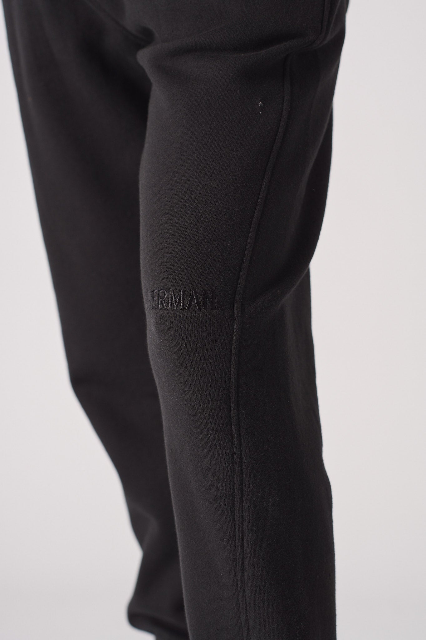 Close-up of the tonal black embroidered logo on the tapered joggers