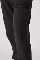 Close-up of the tonal black embroidered logo on the tapered joggers