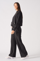 Side view of a model walking in the black jumper for women.