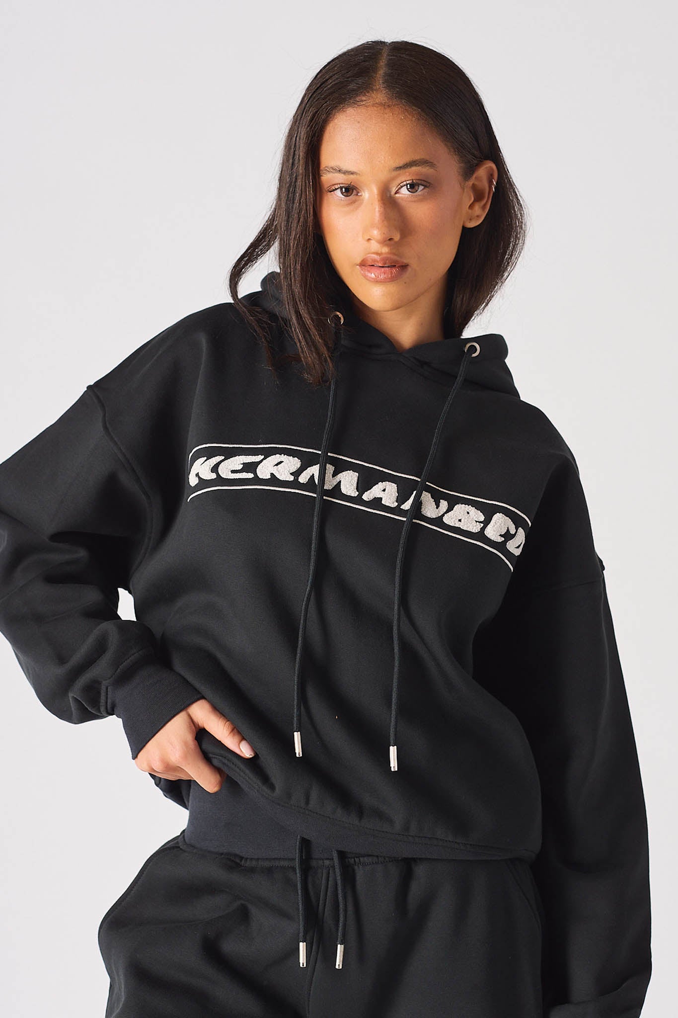 Mid shot of model showing the white chest logo on black oversized hoodie