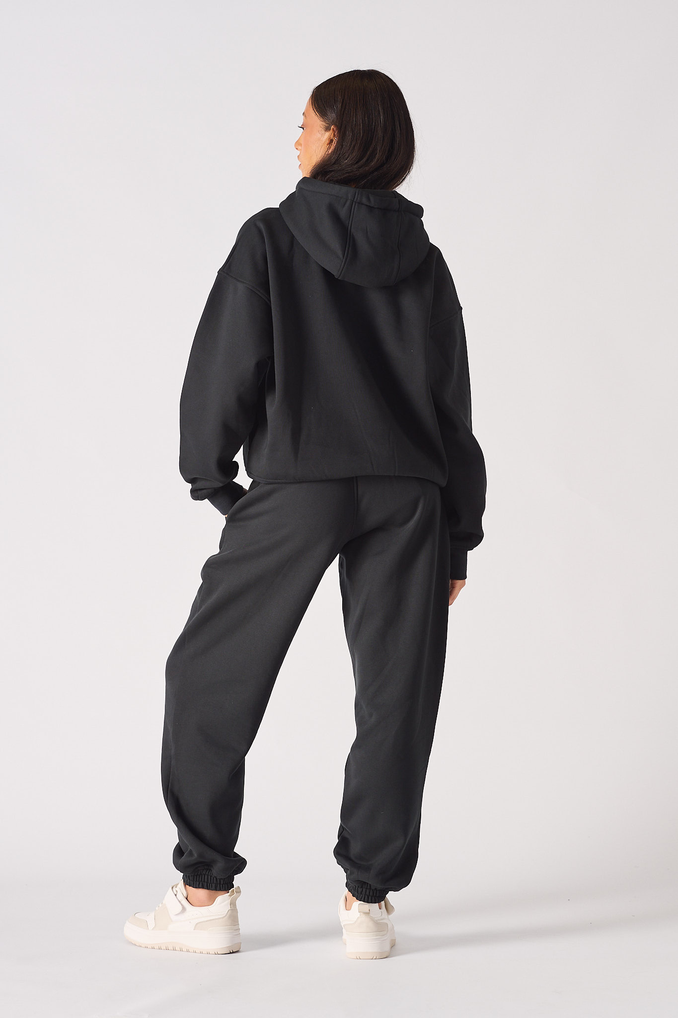 Rear full body view of model wearing a comfortable black oversized hoodie