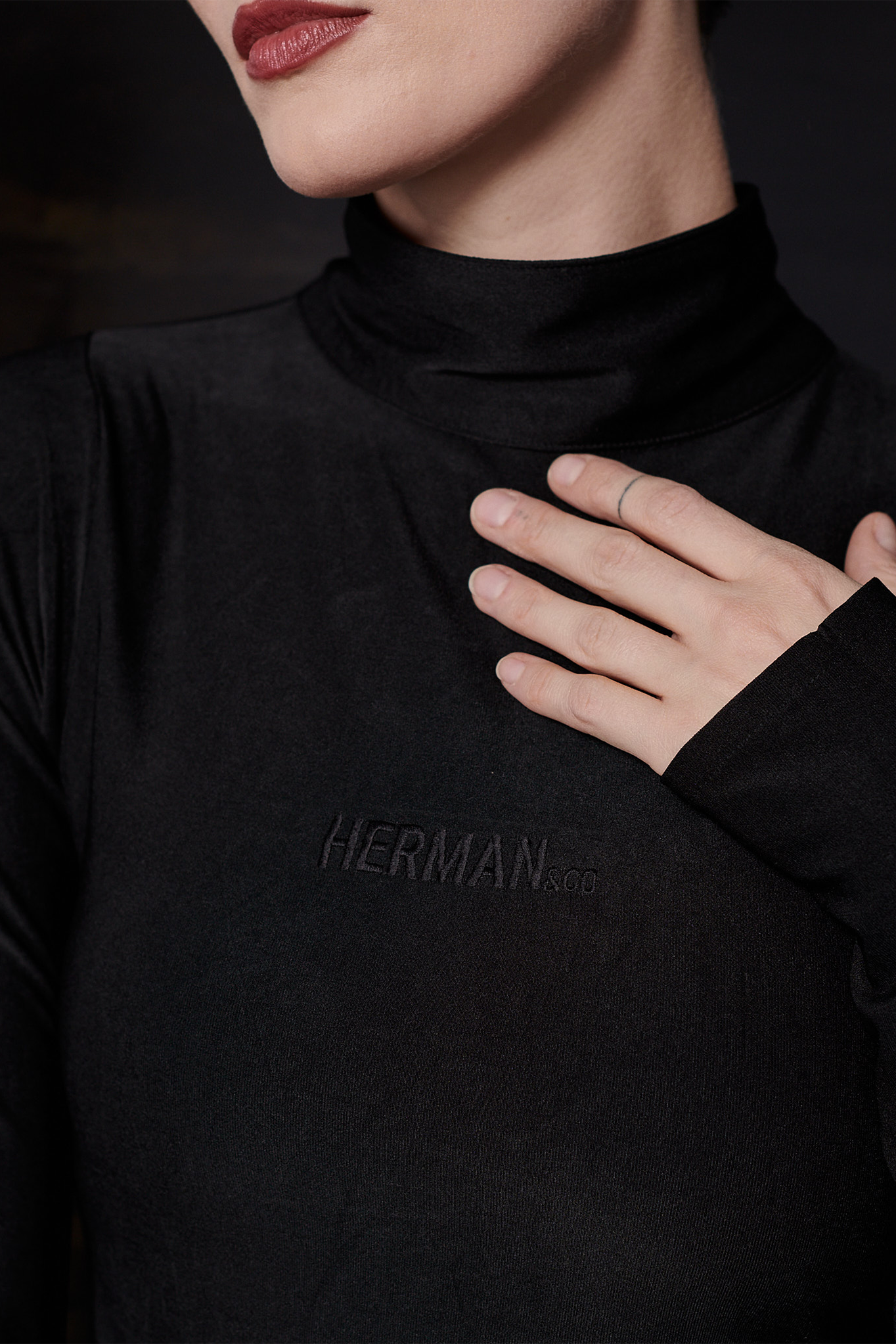 Close-up of the tonal embroidered logo on the black spandex body suit.