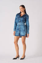 Side angle of a model wearing the blue acid wash denim dress with a popper belt.
