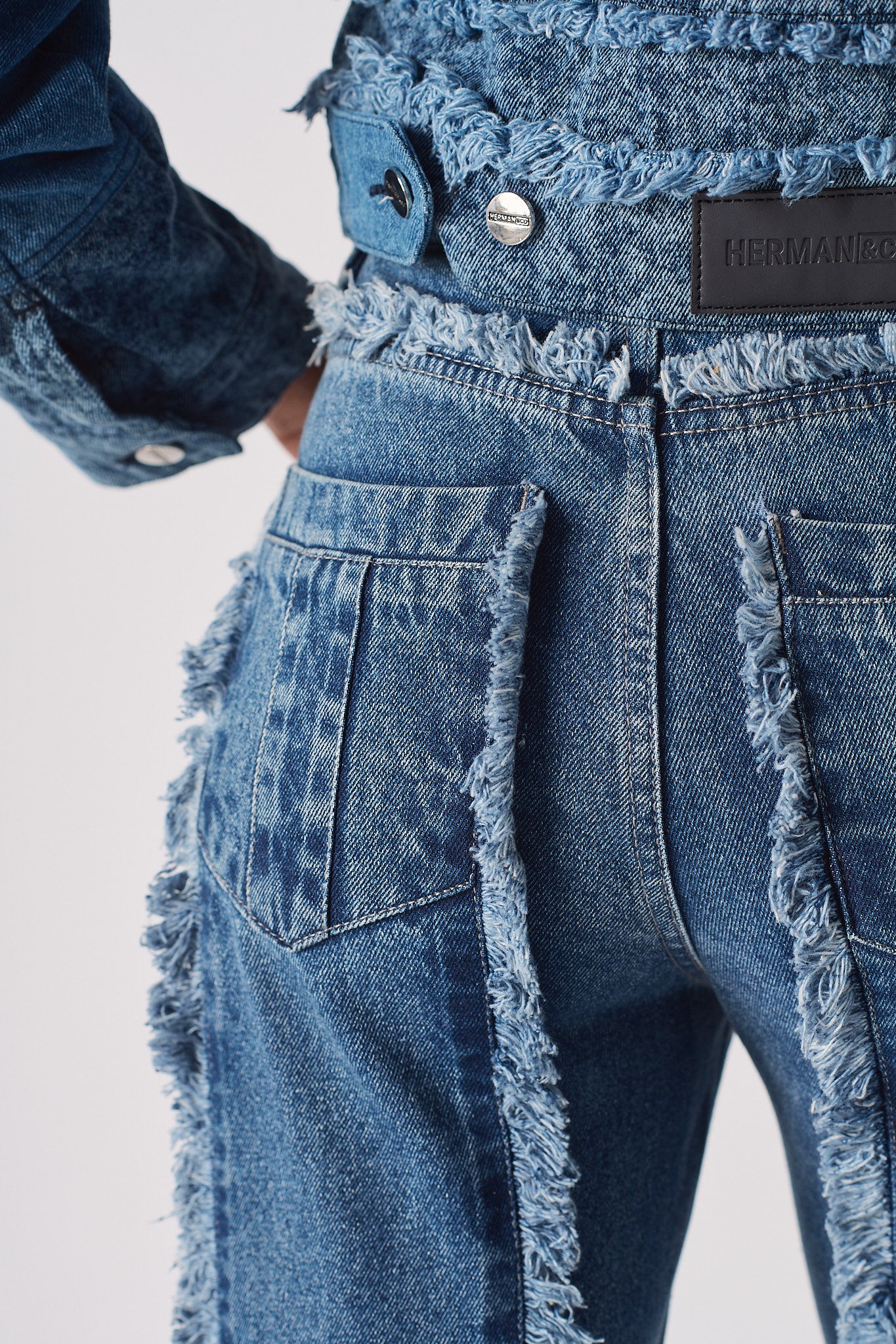 Detailed view of the back pocket and frayed seam on the blue distressed jeans.