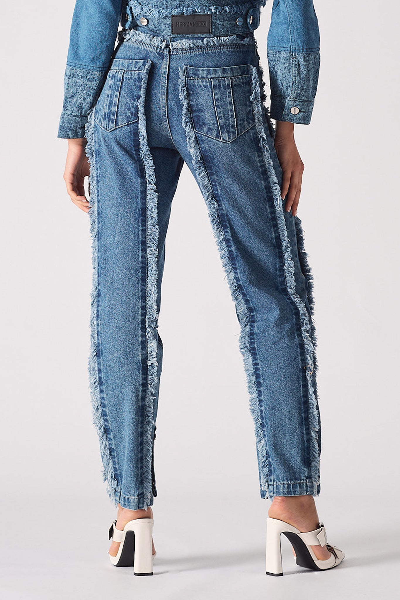 Back view of a model wearing the blue distressed straight leg jeans.