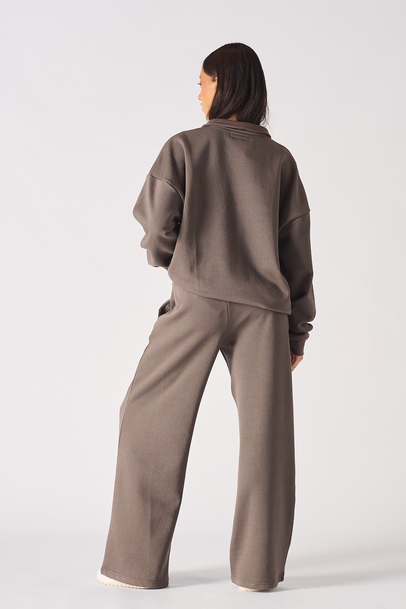 Rear view of model wearing a relaxed fit brown half zip women's sweatshirt outfit