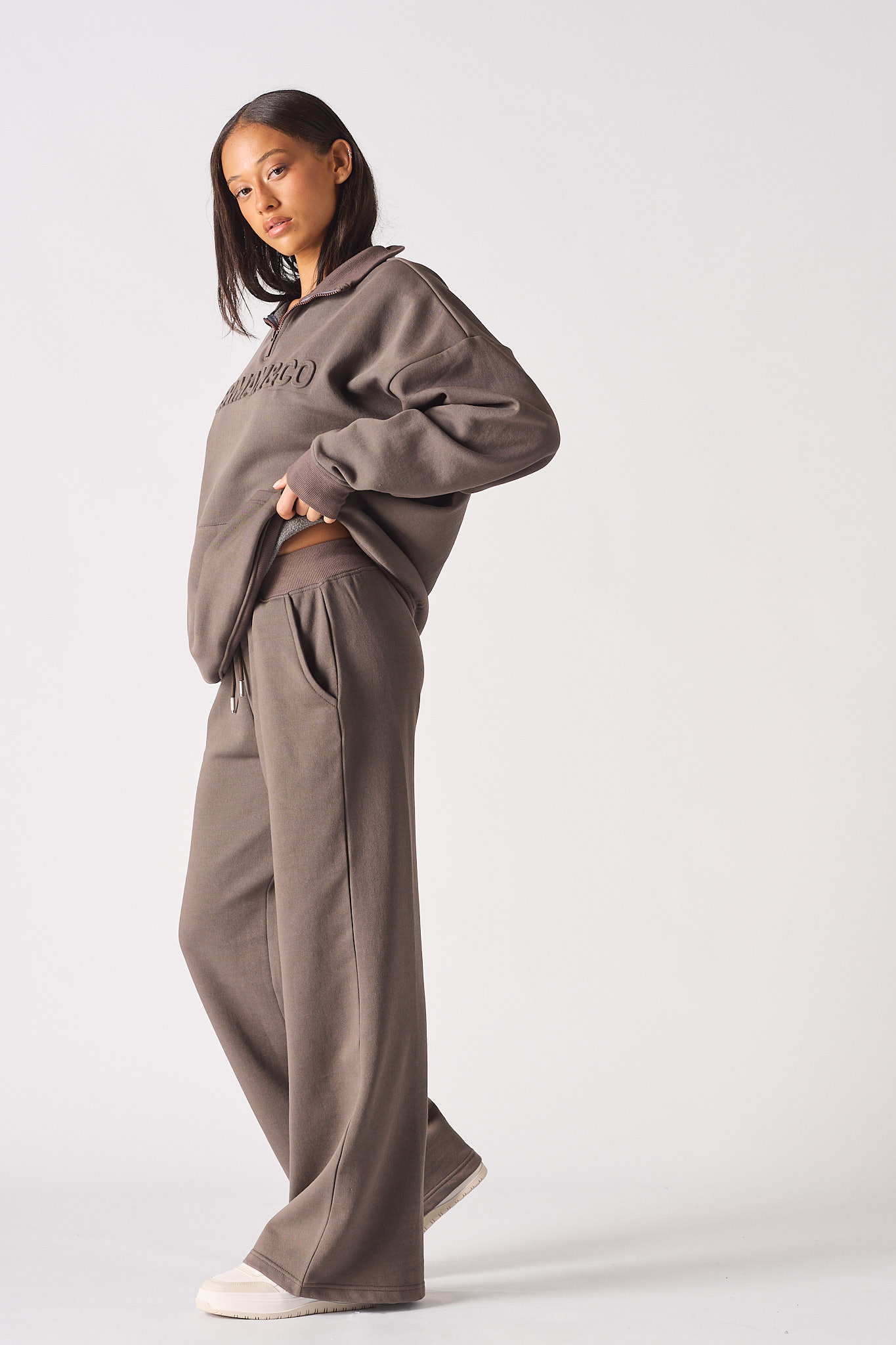 Rear angle view of model walking in brown half zip women's sweatshirt set