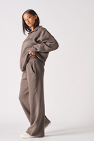 Rear angle view of model walking in brown half zip women's sweatshirt set