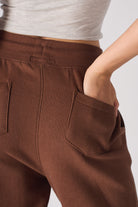 Close-up of the back pocket detail on the brown tapered joggers.