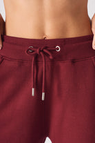 Close up view of the back pocket stitching on burgundy joggers