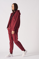 Angled front view of womens burgundy joggers showing tapered leg silhouette