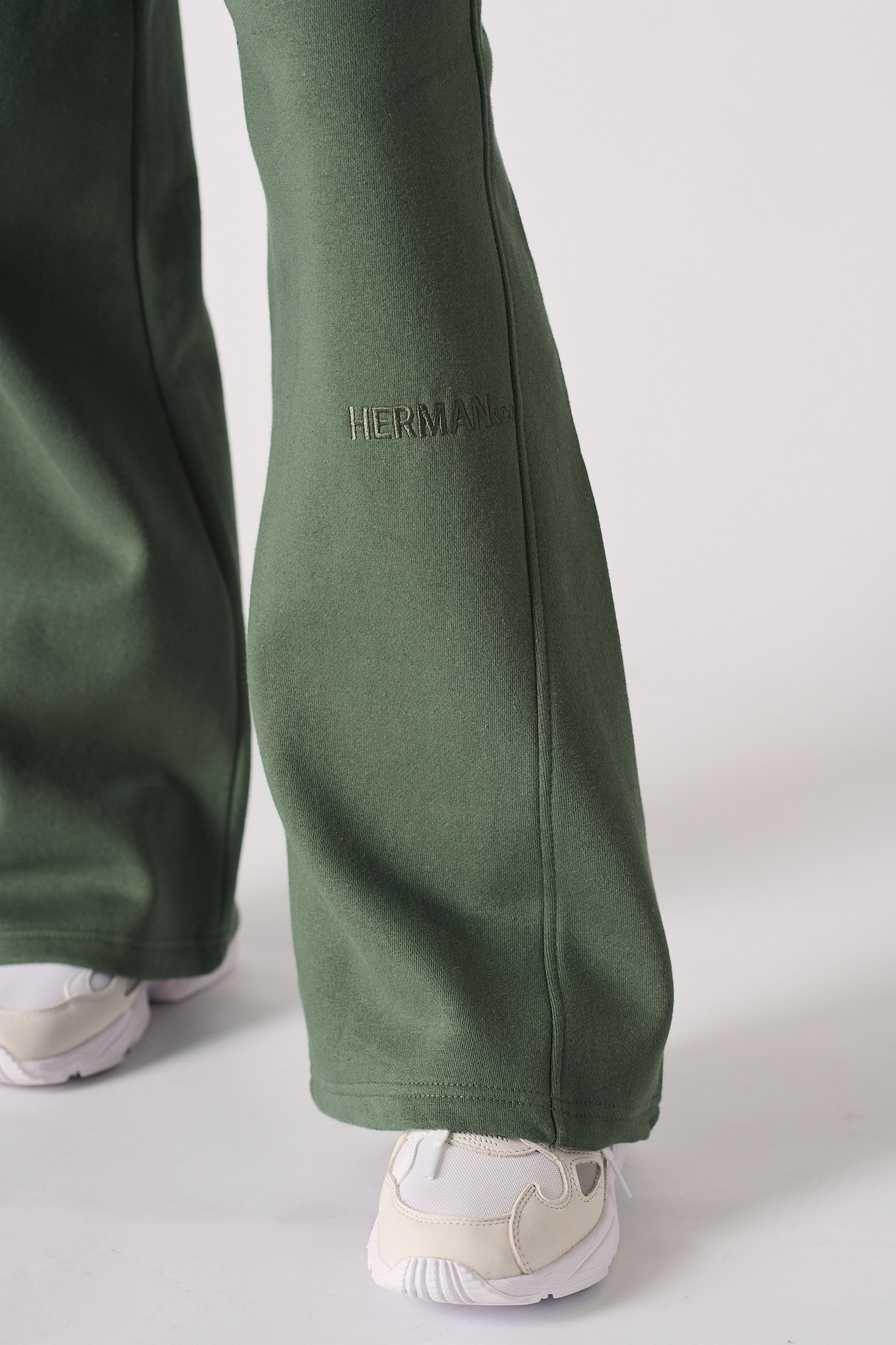 Close-up of the wide-leg hem on the dark green joggers.