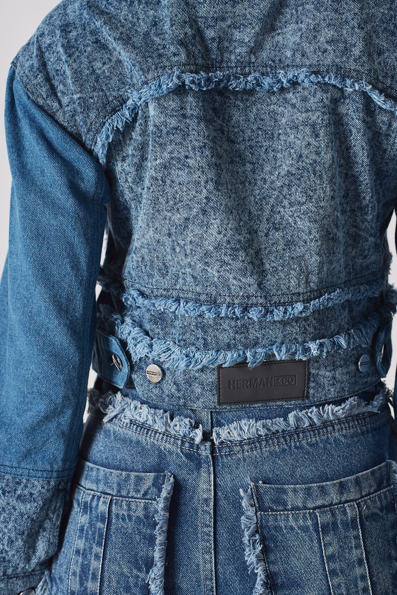 Close-up of the back patch and frayed hem on the distressed denim jacket.