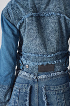 Close-up of the back patch and frayed hem on the distressed denim jacket.