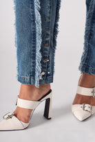 Close-up of the popper button detail on the hem of the distressed straight leg jeans.