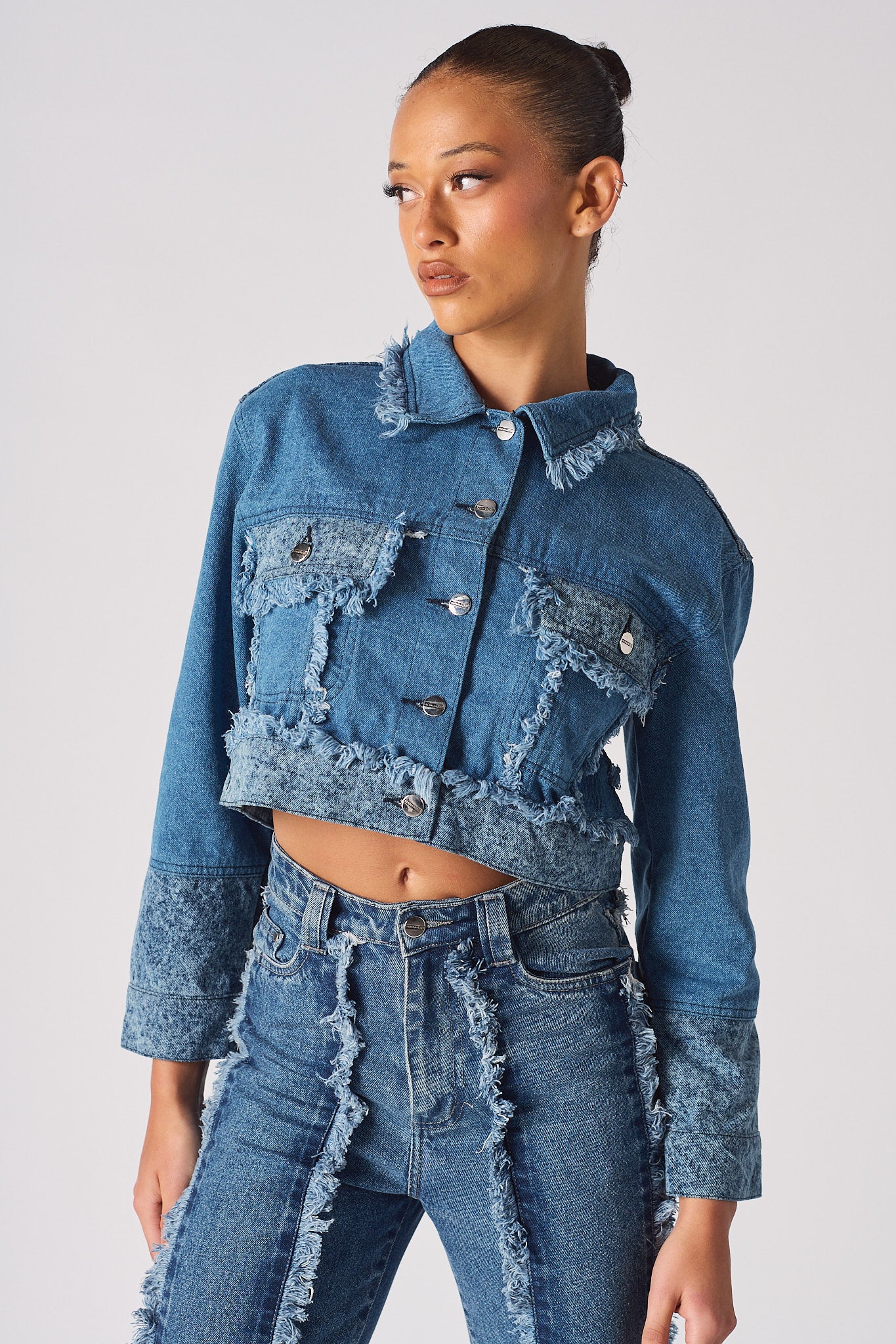Angled front view of the distressed two-tone denim crop jacket.