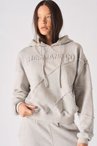 Close up detail of the embossed HERMAN logo on the chest of womens grey hoodie