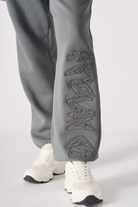 Close-up of the embroidered detail on the leg of the cuffed joggers.