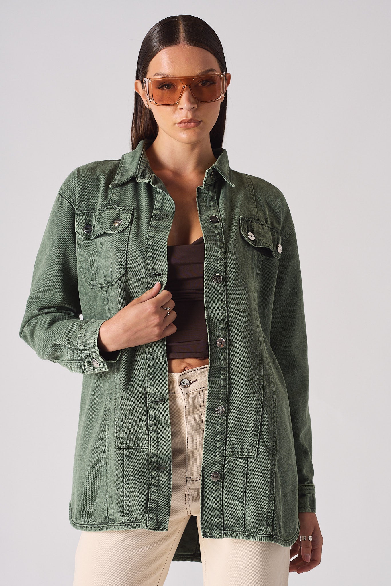 Close-up of a model wearing the green denim shirt for women with sunglasses.