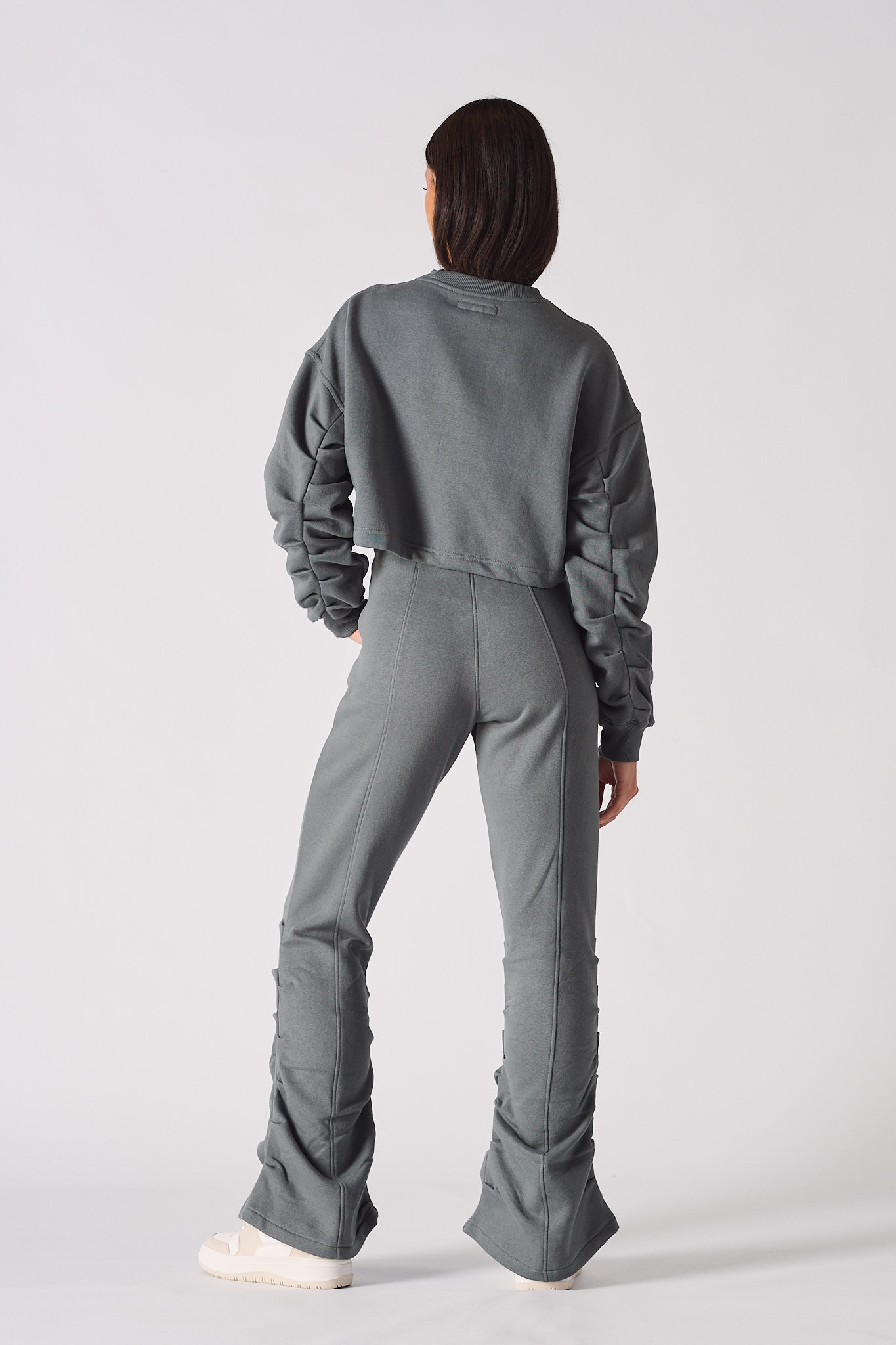 Rear view of model wearing grey crew neck jumper womens with matching flared trousers