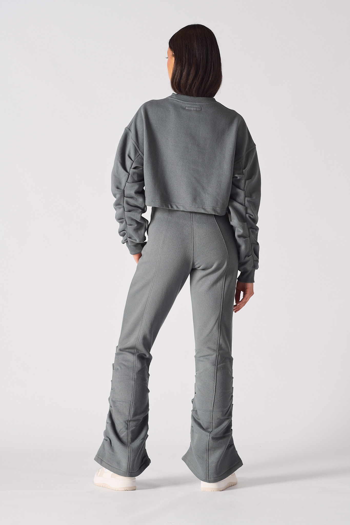 Rear view of model wearing grey ruched flare pants with a relaxed fit