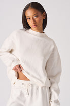 Close up of the high neck and logo embroidery on white crew neck jumper womens