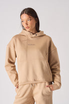 Detailed view of the tonal logo embroidery on the chest of womens beige hoodie