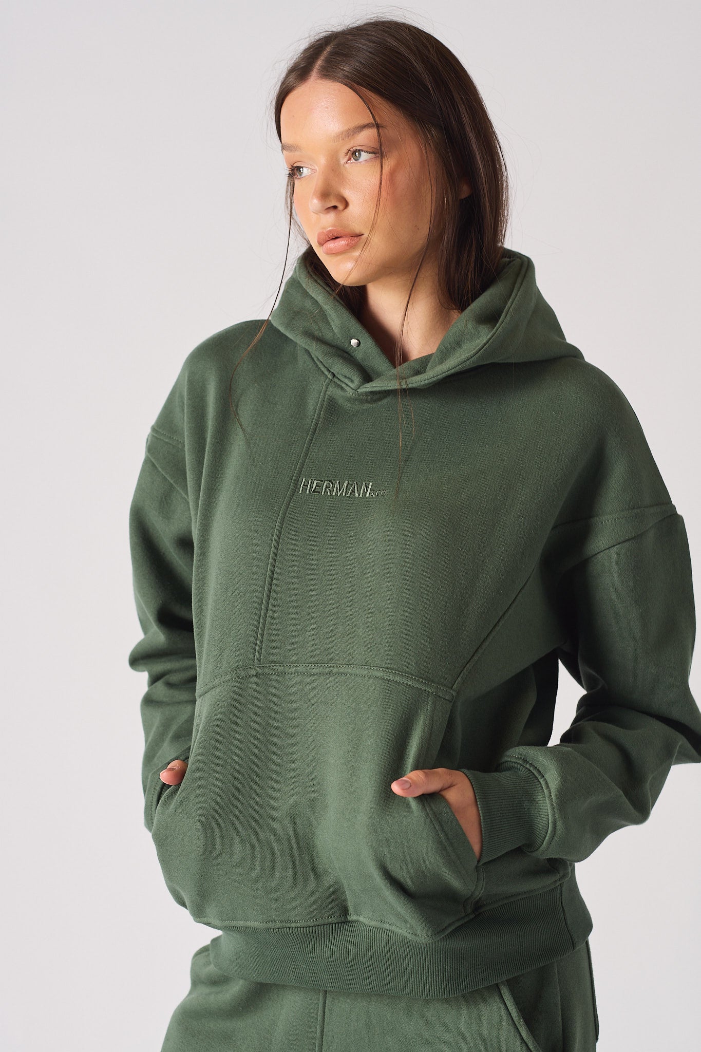 Detail of HERMAN text embroidery on the chest of green hoodie