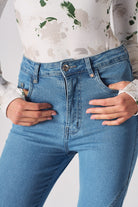 Close-up of the back pockets and logo patch on the high-waisted skinny jeans in blue.