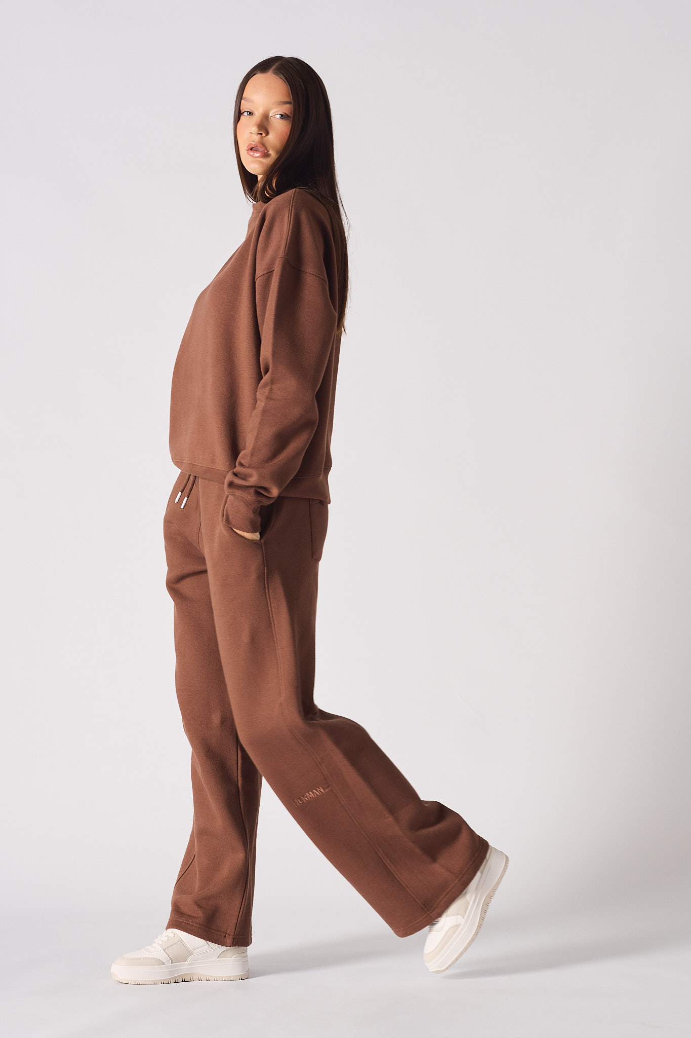 Side profile of a model walking in the ladies' brown wide-leg joggers.