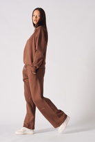 Side profile of a model walking in the ladies' brown wide-leg joggers.