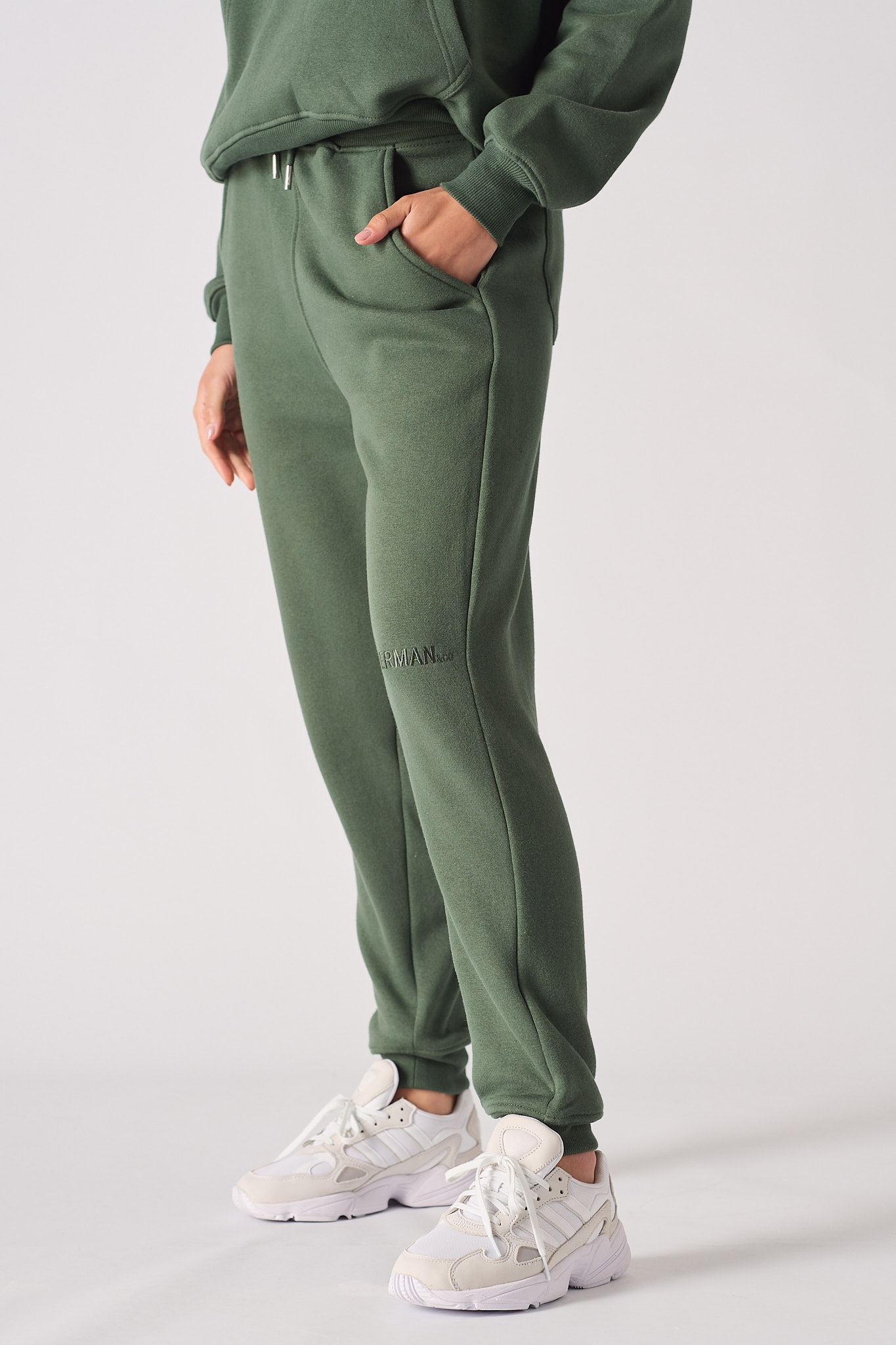 Side profile of a model walking in the ladies' dark green tapered joggers.