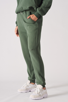 Side profile of a model walking in the ladies' dark green tapered joggers.