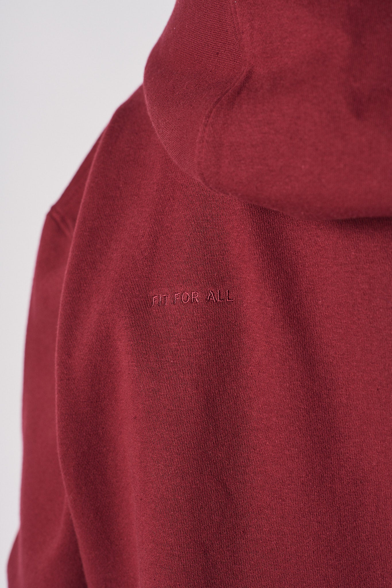 Close-up of the tonal 'Fit For All' embroidery on the ladies' red hoodie.