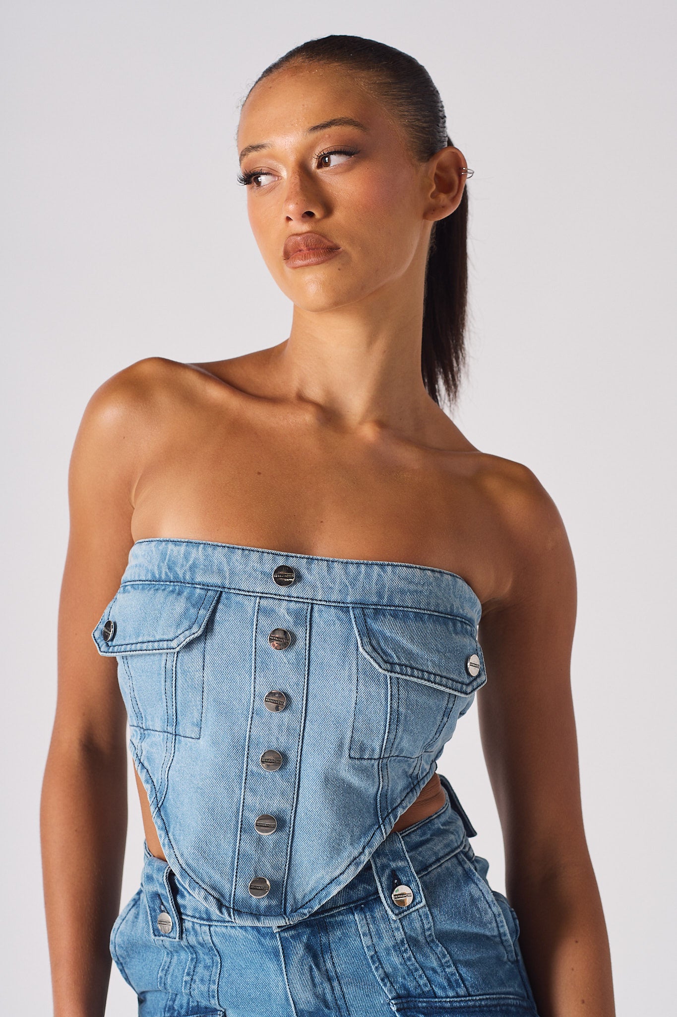 Close-up of a model wearing the light blue strapless denim corset with pockets.