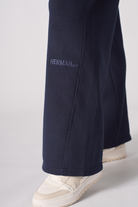 Close-up of the tonal embroidered logo on the navy wide-leg joggers.