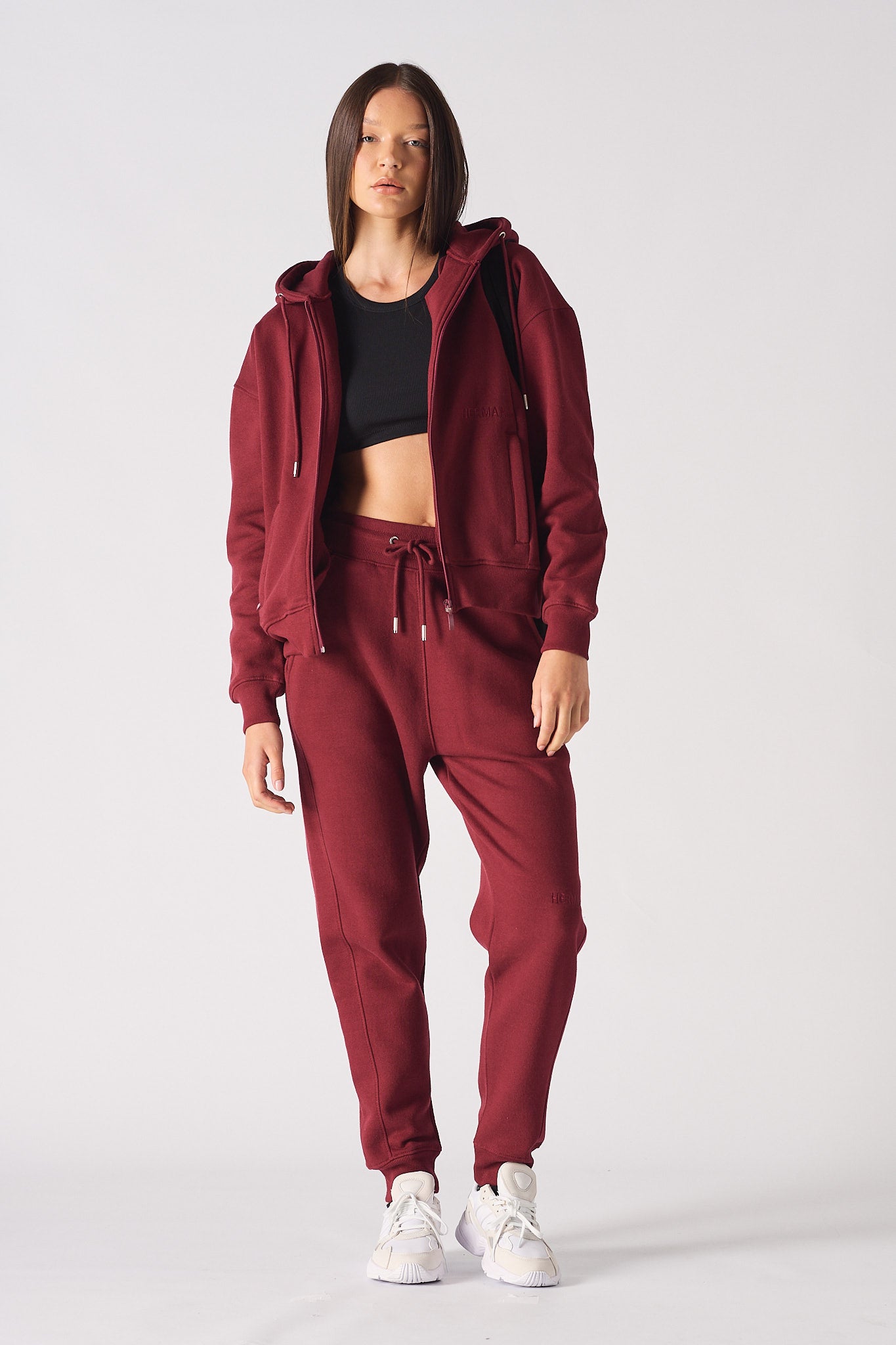 A model wearing the red zip-up hoodie for women with matching joggers.