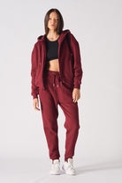 A model wearing the red zip-up hoodie for women with matching joggers.