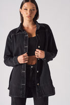 A model styling the black contrast stitch denim shirt worn open.