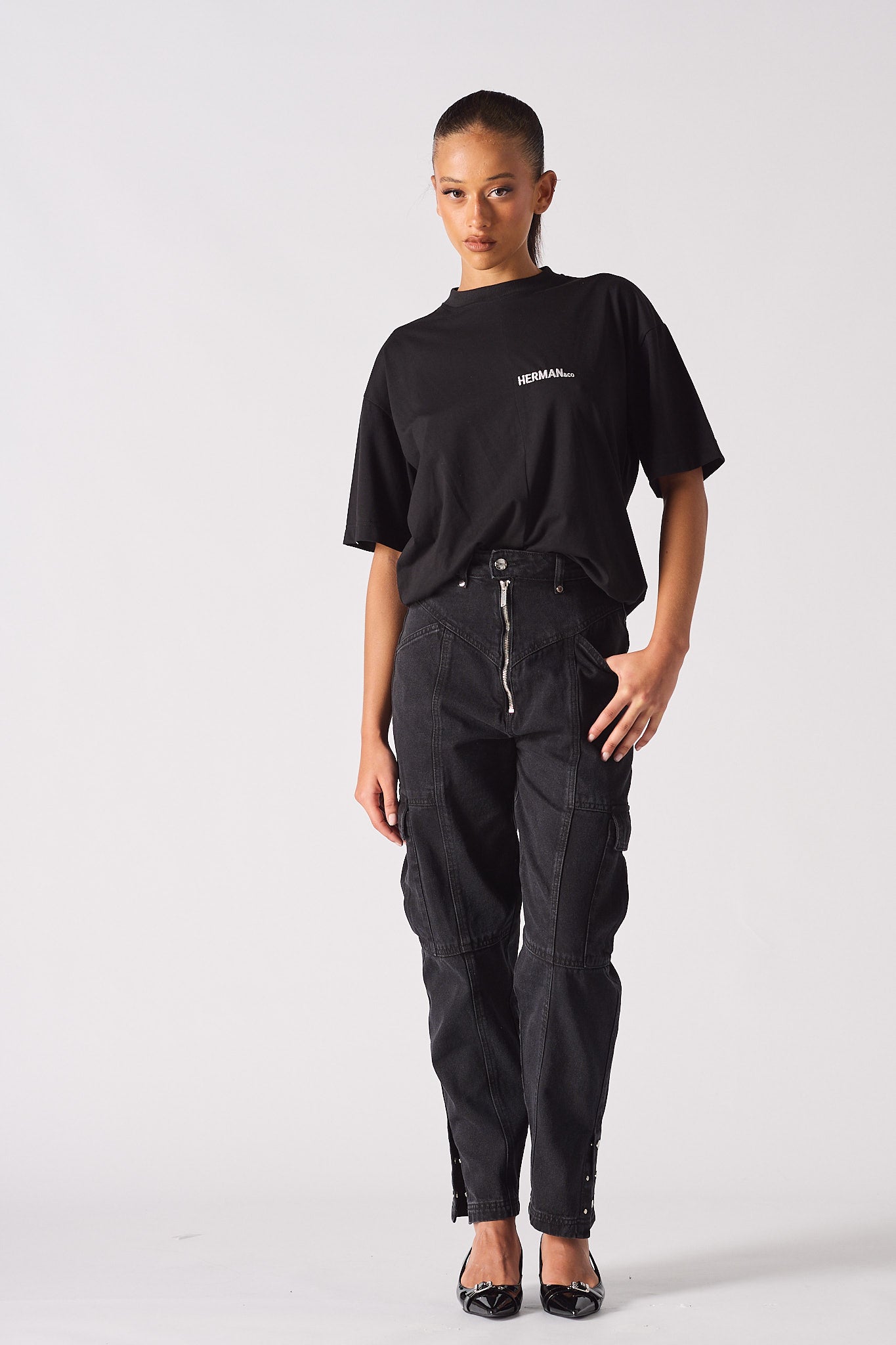 A model styled in the black zip front cargo jeans with a black t-shirt.