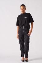 A model styled in the black zip front cargo jeans with a black t-shirt.