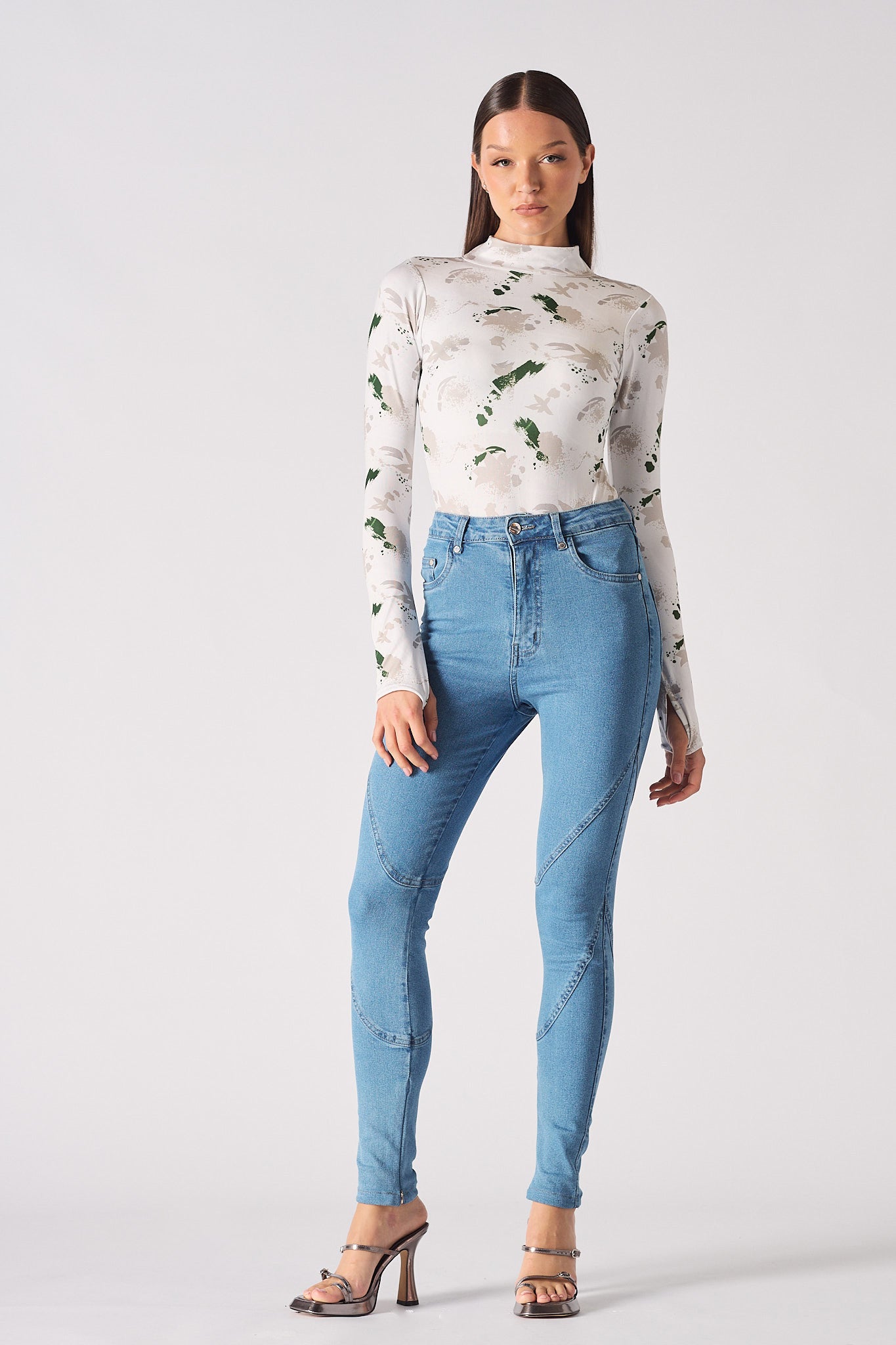 A model styled in the high-waisted blue skinny jeans with a printed top.