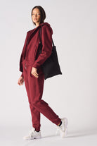 A model styled in the ladies' red zip-up hoodie with a tote bag.