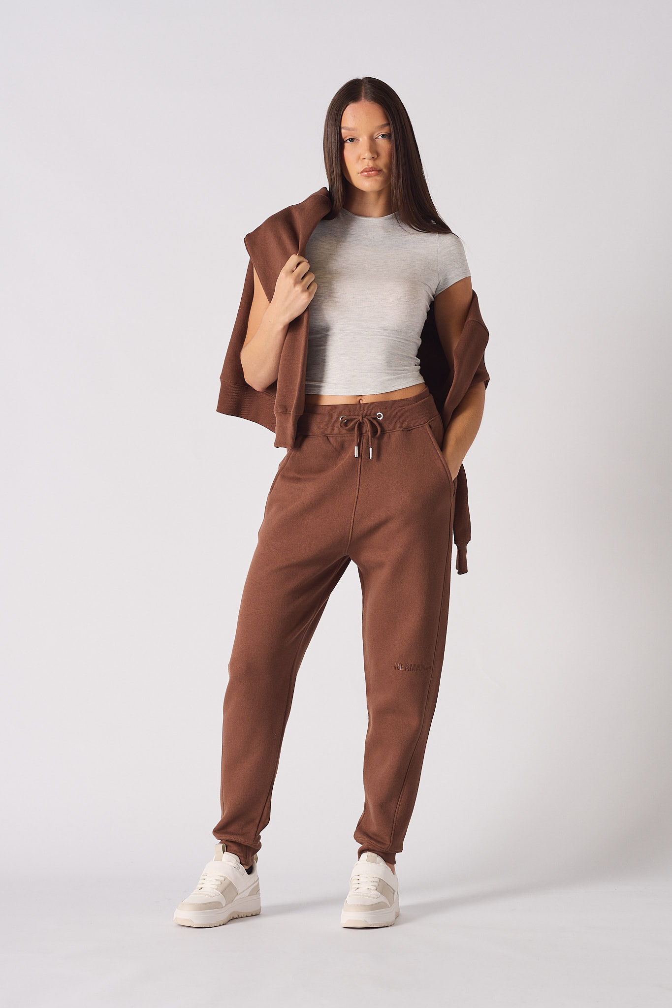 A model styling the women's brown tapered jogger with a white top.