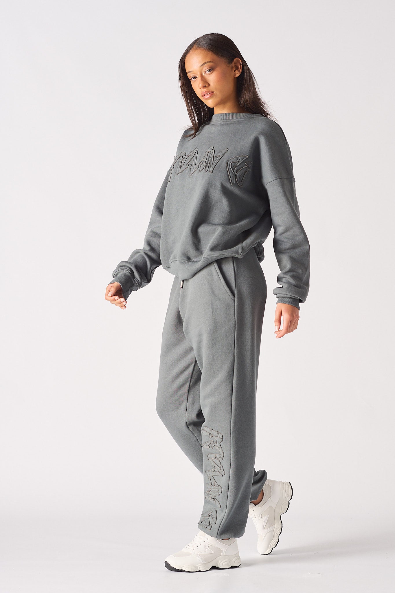A model styled in the women's grey cuffed joggers with a matching sweatshirt.
