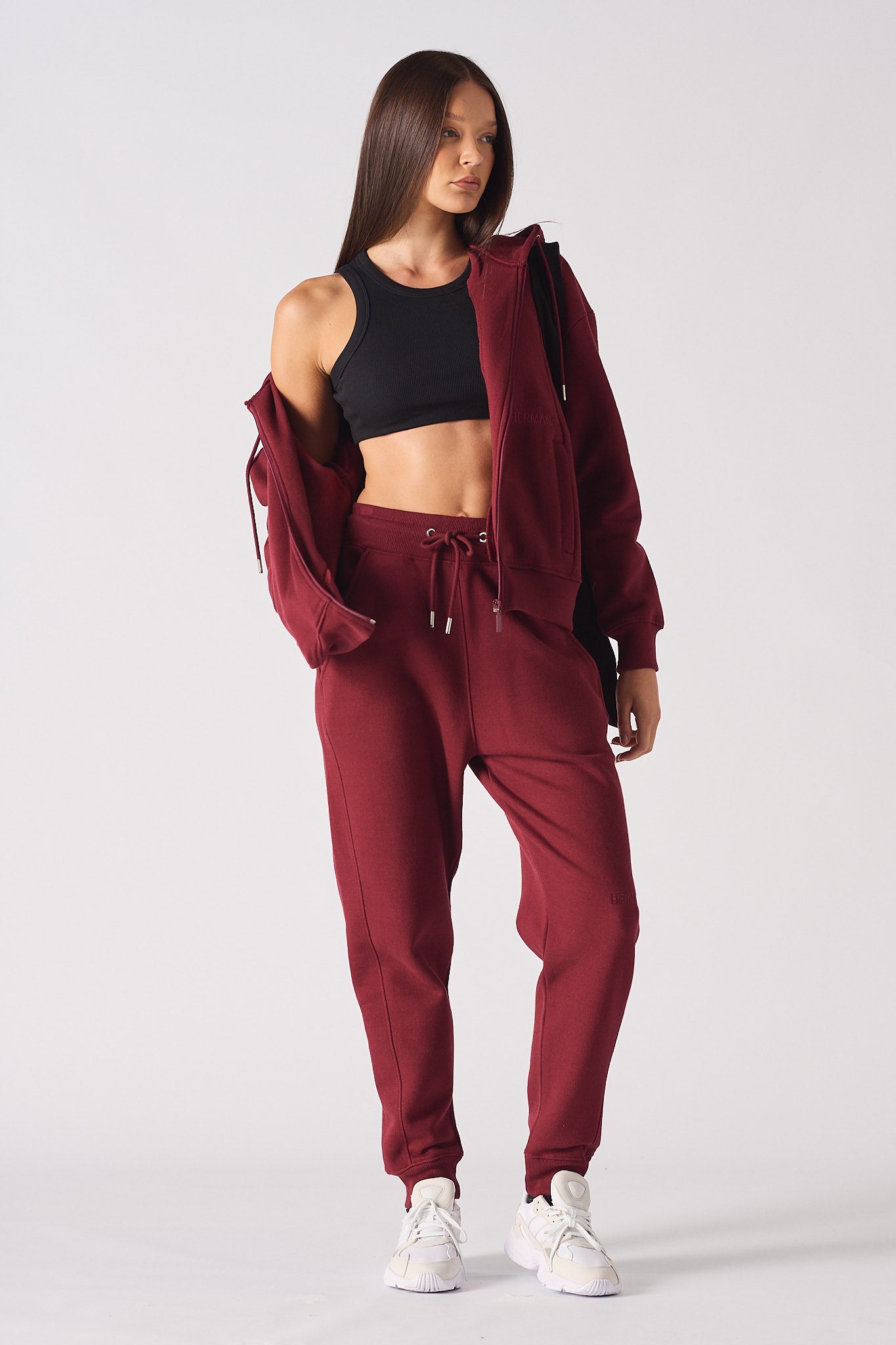 A model styling the women's red zip-up hoodie off the shoulder.