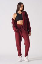 A model styling the women's red zip-up hoodie off the shoulder.