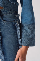 Close-up of the sleeve and frayed cuff detail on the two-tone denim jacket.