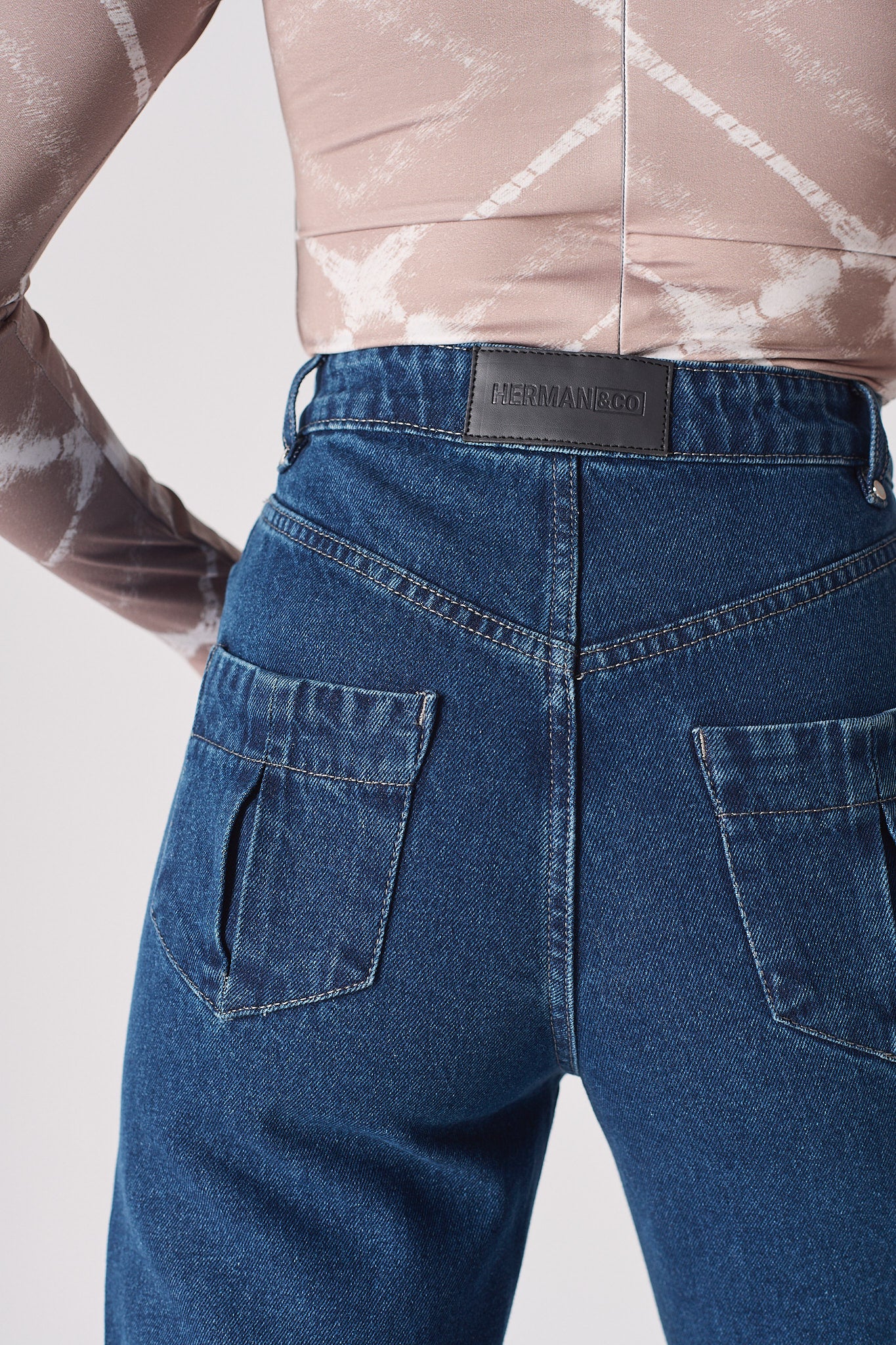 Close-up of the back pocket and logo patch on the whisker jeans for women.